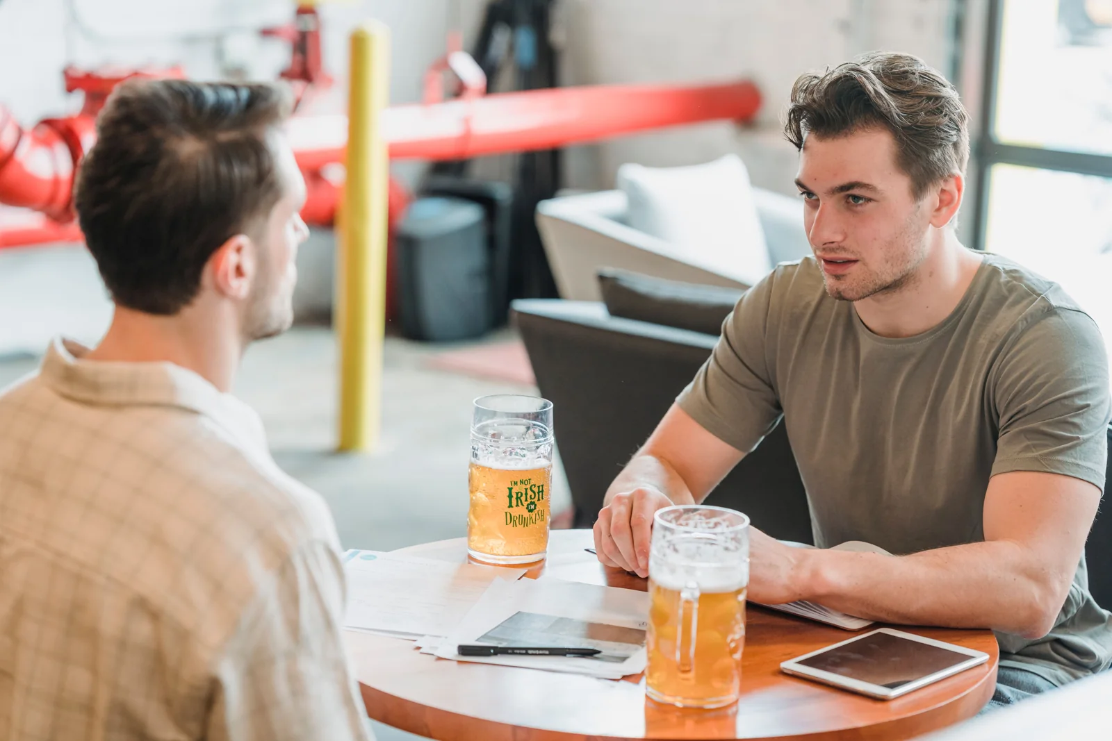 Conversación sobre un proyecto con notas y cerveza en la mesa